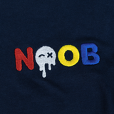 NOOB Multi Logo embroidered on the font of a navy t-shirt showing close up of stitching.